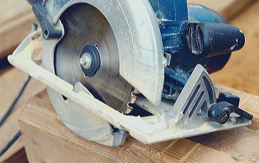 A blue circular saw sits on top of some lumber.